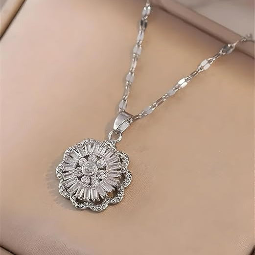 A rotating flower pendant necklace with a stainless steel chain displayed on a beige surface.