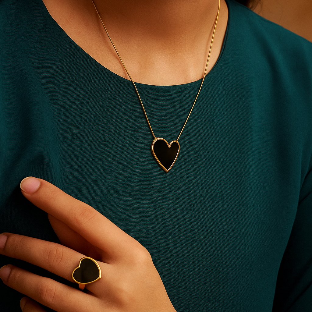 Person wearing a gold necklace with a heart pendant and matching ring.