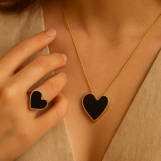 Woman wearing a gold necklace with a heart pendant and matching ring.