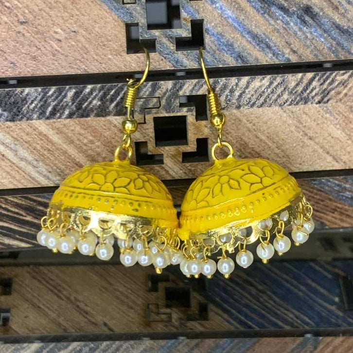 Gold earrings with pearl accents on a wooden background