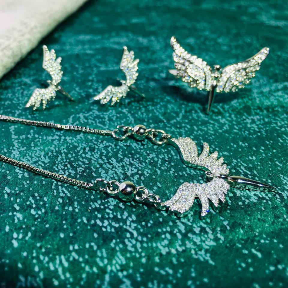 Silver jewelry set with necklace and earrings on a textured green surface