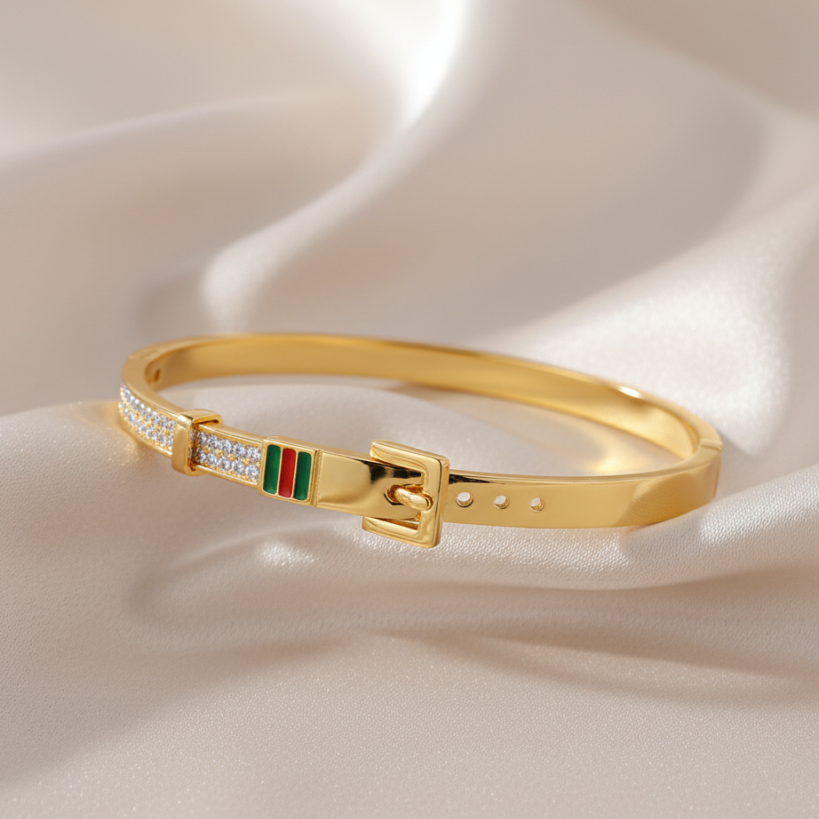 Gold bracelet with a buckle design and colorful accents on a beige fabric background